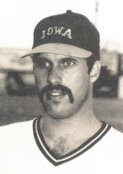 Un joueur de baseball portant un maillot blanc et une casquette sombre