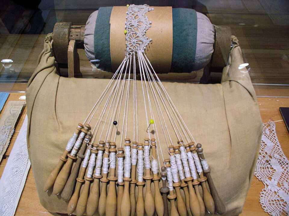 dentelle aux fuseaux réalisée sur un coussin à rouleaux