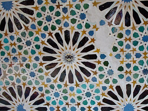 Zellige à motifs d'étoiles à 16 branches dans le Mexuar de l'Alhambra de Grenade (XIVe siècle ; avec emblème espagnol ultérieur inséré au centre)