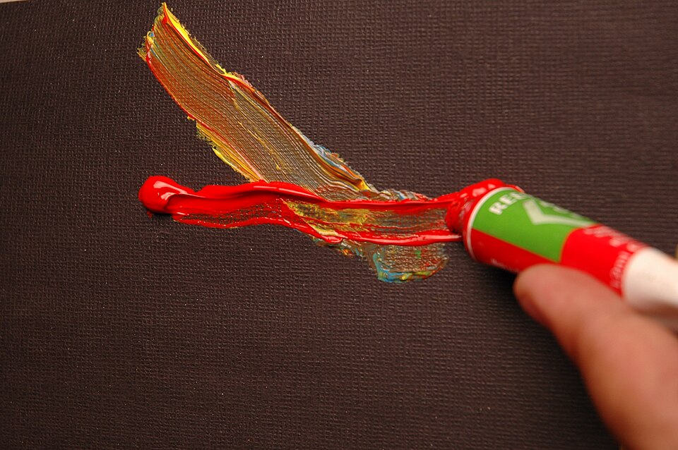 On presse le tube de peinture rouge à la main sur la ligne de peinture précédente, sur la bordure foncée.