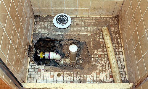 Réparation de douche montrant la tuyauterie d'évacuation avec siphon