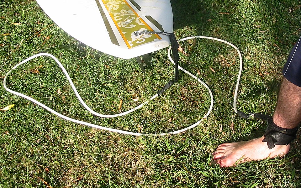 Photo d'un cordon en plastique attaché à une planche de surf et fixé par velcro autour de la cheville du surfeur