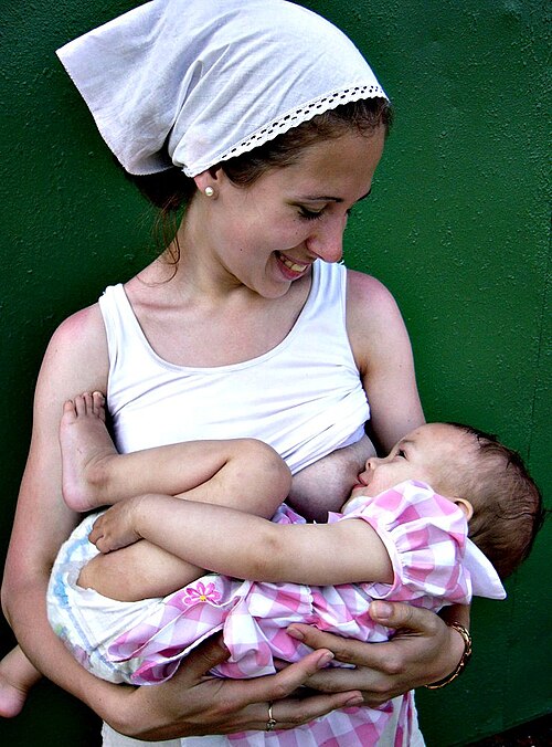 une mère souriante tient son bébé pour l'allaiter