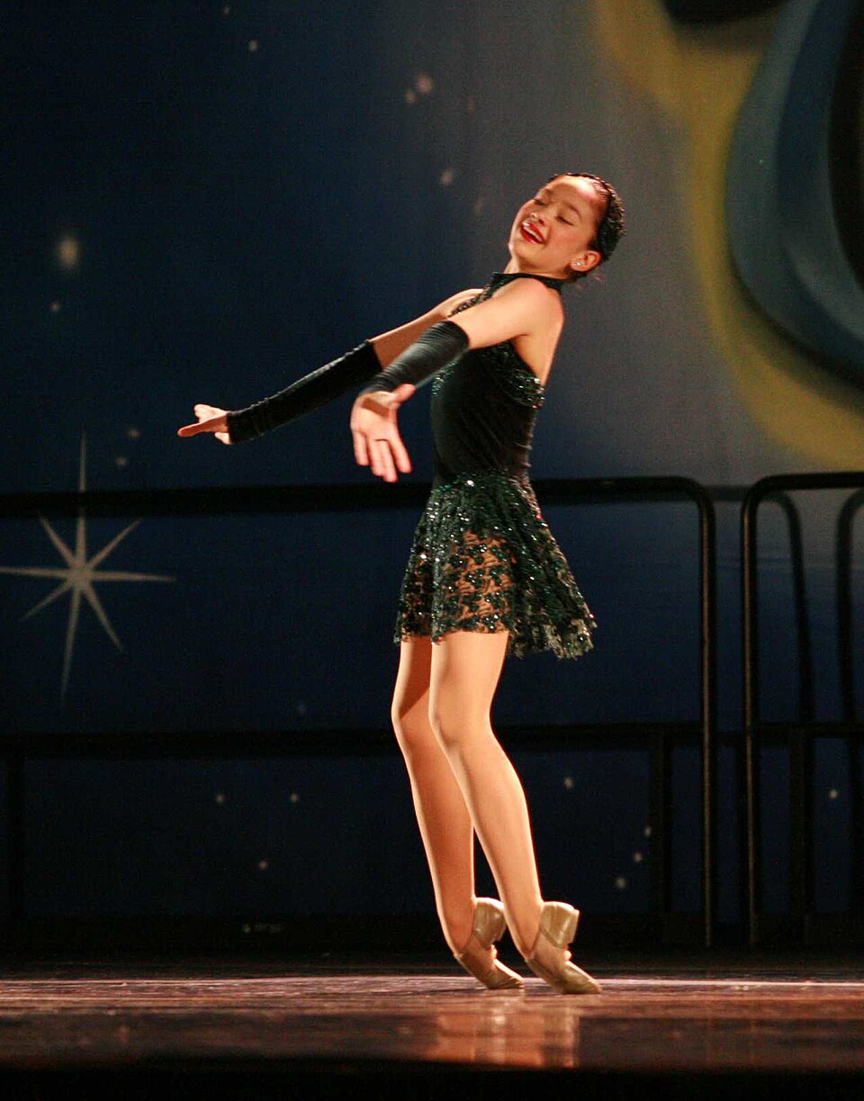 Une danseuse exécute un « relevé sur la pointe des pieds », au cours duquel elle passe d'une position à genoux à une position debout sur la pointe des pieds.