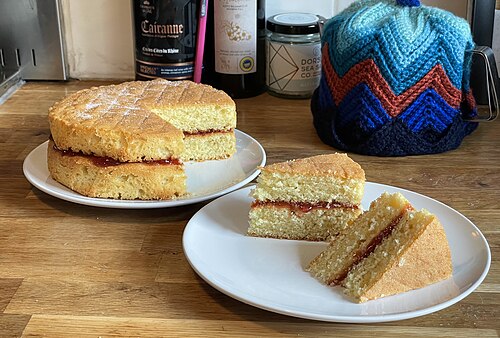 Gâteau sandwich Victoria à deux étages avec une garniture de confiture de fraises ; deux tranches ont été prises prêtes à servir et démontrent la construction du gâteau