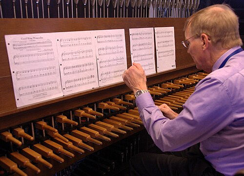 Un homme joue avec ses poings sur le clavier en bois d'un carillon.