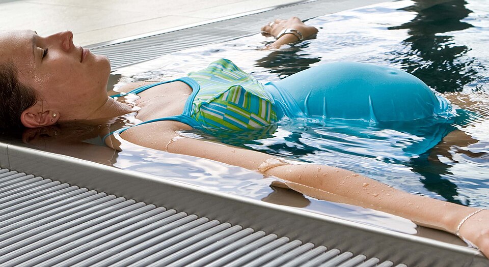 Une femme enceinte flotte dans un coin d'une piscine