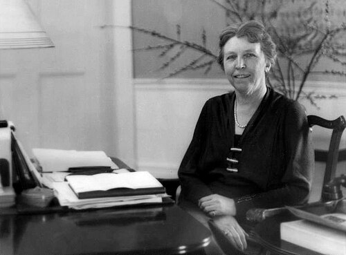 Femme civile assise à un bureau, les mains croisées