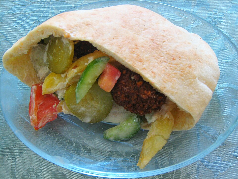 Un pita rempli de légumes et de beignets dans une assiette