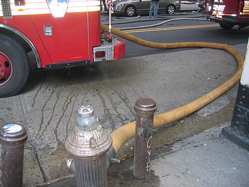 Une bouche d'incendie de la ville de New York reliée à un camion de pompiers du FDNY avec un tuyau d'incendie pompant activement de l'eau