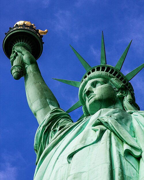 La Statue de la Liberté, une grande sculpture en bronze bleu sarcelle sur un piédestal en pierre