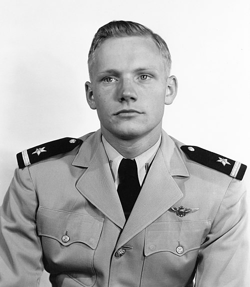 Une image en noir et blanc d'un homme à la peau claire d'une vingtaine d'années. Il regarde vers sa droite. Il a les cheveux mi-colorés séparés vers la droite. Il porte un uniforme militaire de couleur claire avec un badge d'aigle sur la poitrine gauche. Ses épaulettes sont sombres et ont une barre claire et une étoile. Il a une chemise blanche et une cravate sombre.