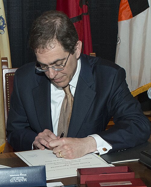 Une image qui montre Christopher Eisgruber en train de signer un papier