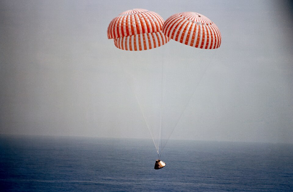 Un vaisseau spatial descend au-dessus de l'océan avec des parachutes