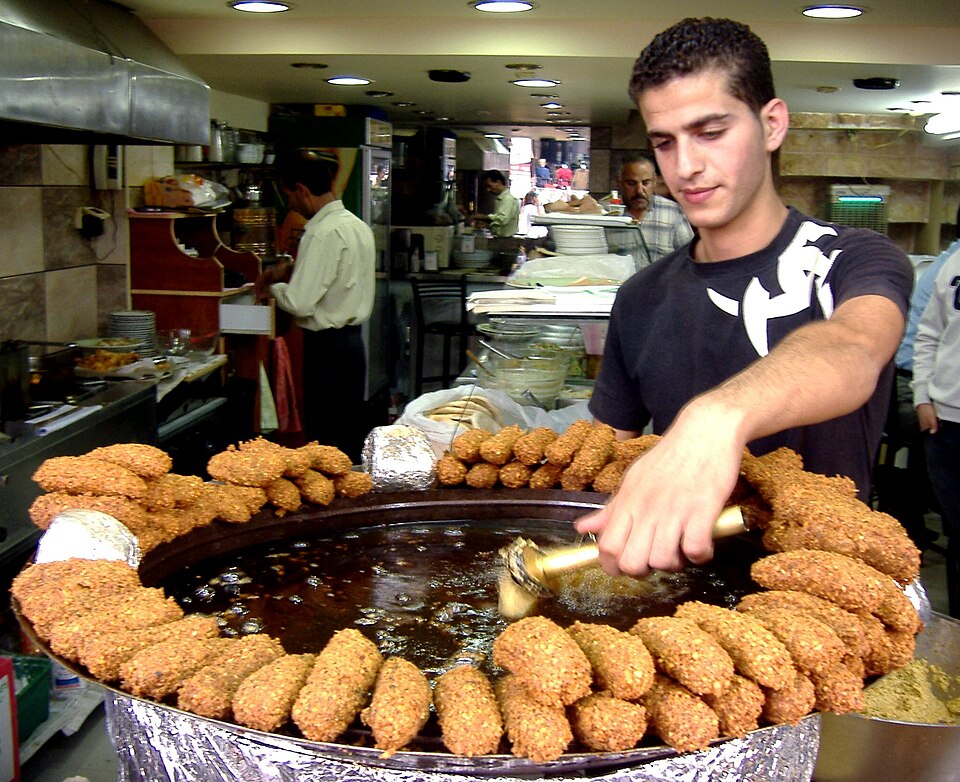 Un homme dans la cuisine d'un restaurant en train de préparer des beignets