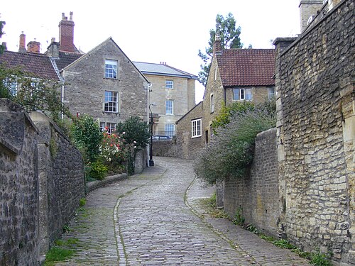 Ruelle étroite entre murs de pierre et maisons