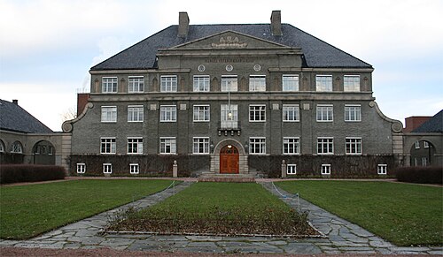 Grand bâtiment gris derrière une zone herbeuse