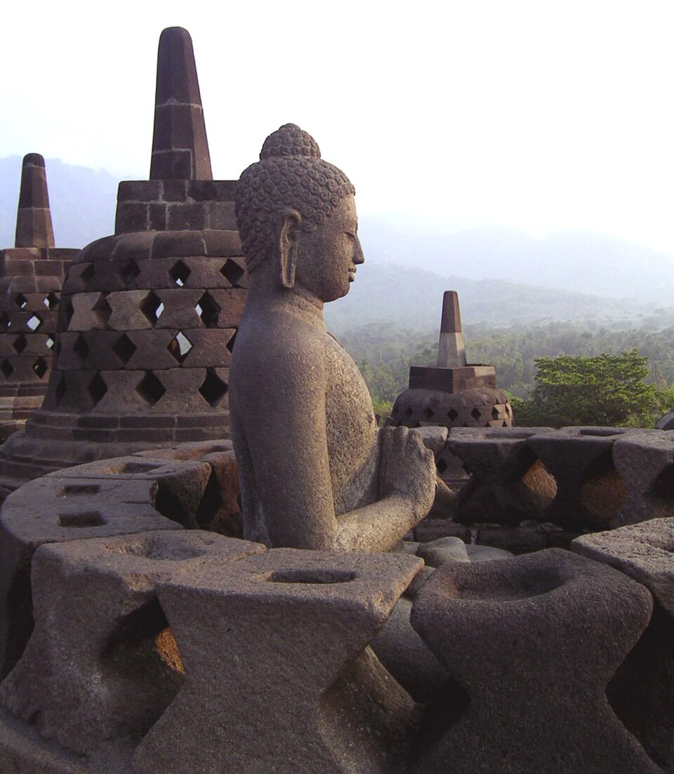 À Borobudor, des centaines de statues de Bouddha se trouvent à l'intérieur de stupas ajourés ; ici, le plus proche est partiellement déconstruit.