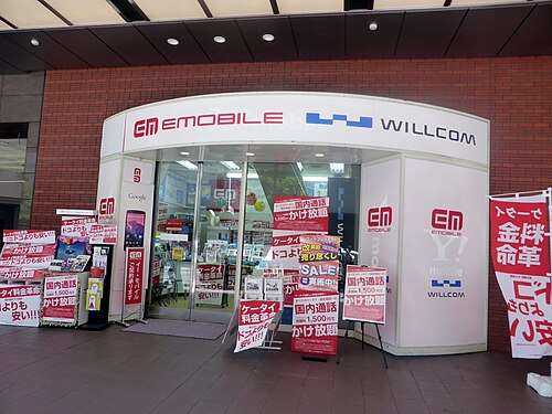 Panneaux Willcom et EMOBILE sur une place en 2014