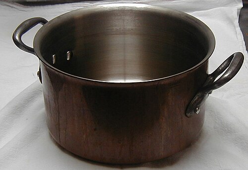 Une casserole en cuivre (revêtement en inox, avec poignées en fonte)