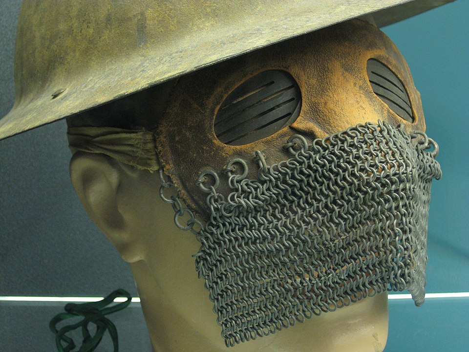 un masque avec une partie supérieure en cuir avec des fentes sur les oculaires en métal et une partie inférieure en cotte de mailles, modelée sur une tête factice avec un casque de guerre en métal