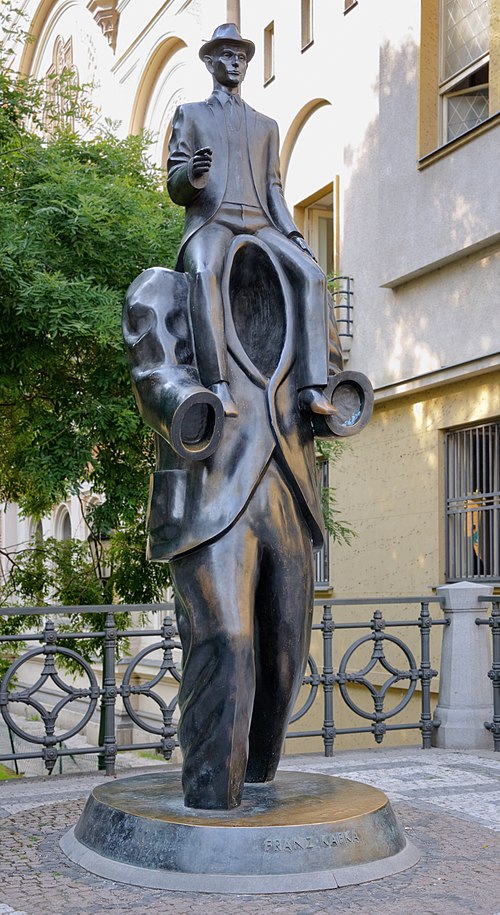La statue représente un homme sans tête ni bras, avec un autre homme assis sur ses épaules