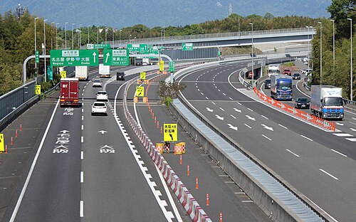 A group of green-colored directional signs on a Japanese expressway