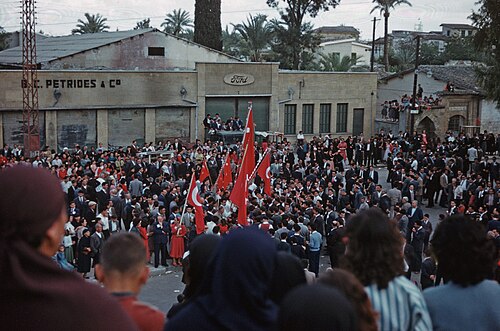 Une foule avec des drapeaux turcs devant un bâtiment
