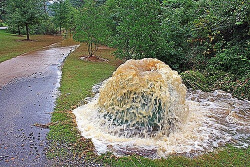 De l'eau sale jaillit d'un couple d'alimentation provenant d'un regard d'égout.
