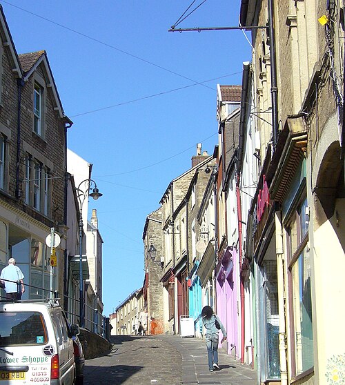 Scène de rue montrant une route pavée étroite le long de façades de magasins colorées