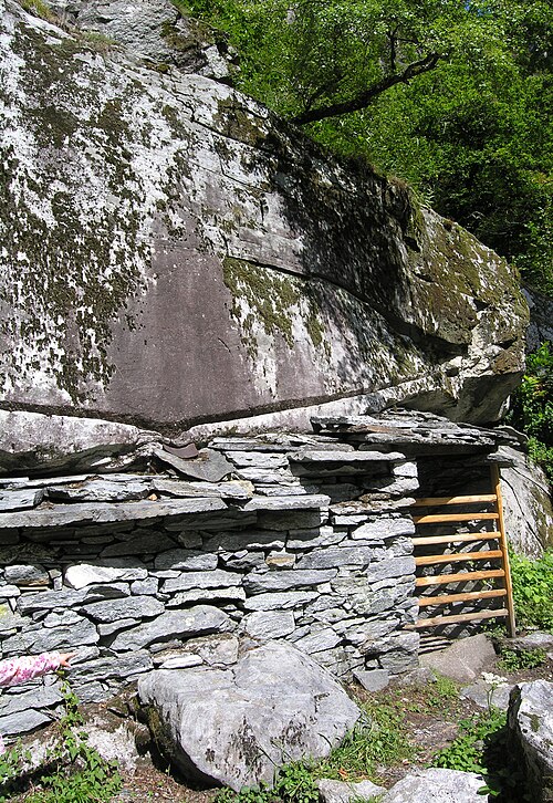Ajout d'un mur en pierre sèche pour transformer l'espace sous un gros rocher en un bâtiment fonctionnel près de Bignasco, Suisse