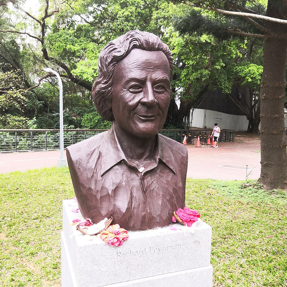 Un buste en bronze avec des fleurs à côté, reposant sur un socle en pierre