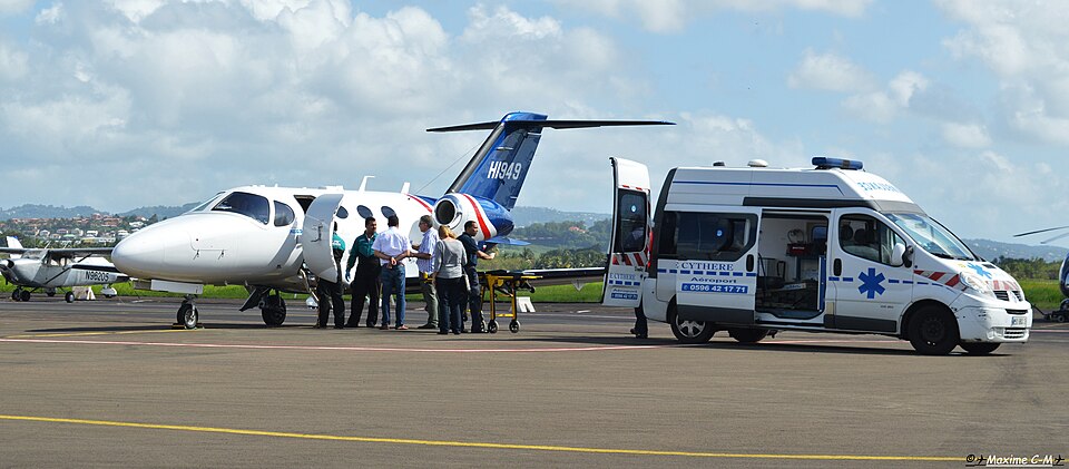A patient is transferred between an aircraft and an ambulance at Le François airport.