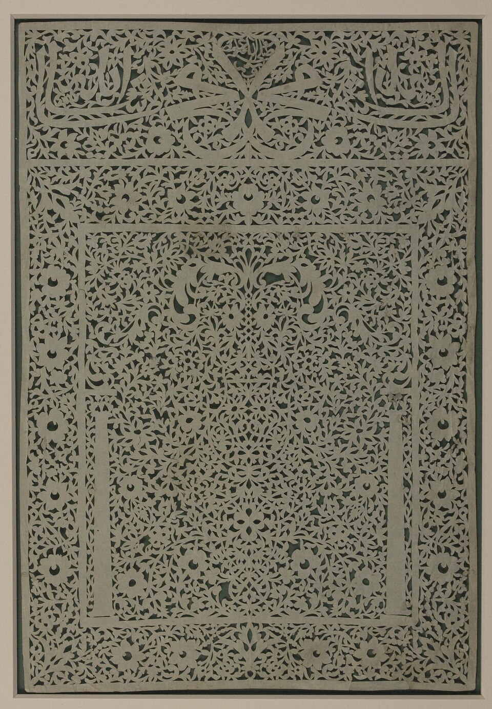 Calligraphie en découpage (XVIIIe ou XIXe siècle) avec le nom de Mahomet en écriture miroir, en haut au centre ; la zone en dessous représente un mihrab, ou niche de prière.
