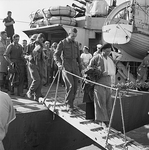 Une photographie en noir et blanc montrant des soldats britanniques blessés débarquant d'un navire de guerre