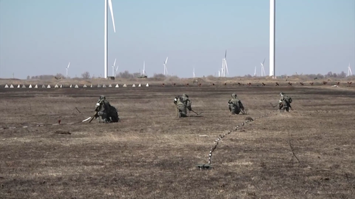 Des militaires russes déminent une zone devant des centrales éoliennes et à côté des dents de dragon.