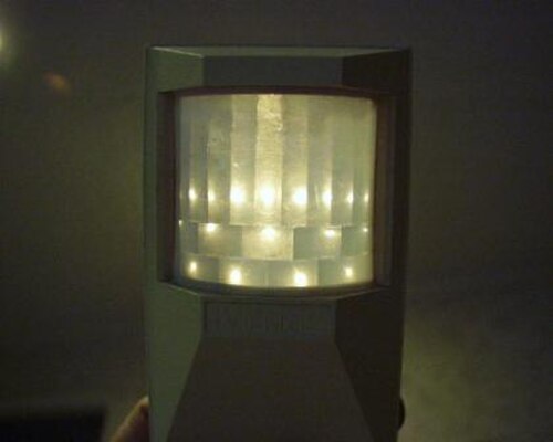 Couvercle avant PIR uniquement (électronique retirée), avec source lumineuse ponctuelle derrière, pour montrer les lentilles individuelles.