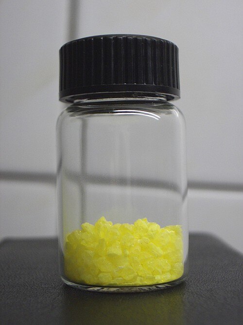 Verre de montre sur une surface noire avec une petite portion de cristaux jaunes