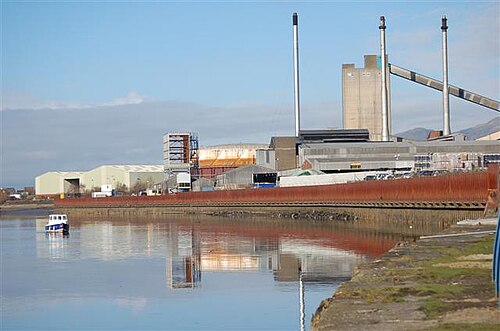 Un bâtiment de verrerie avec de grandes tours au bord d'un plan d'eau