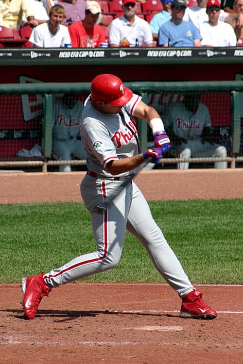 Un homme en uniforme des Phillies de Philadelphie brandissant une batte de baseball