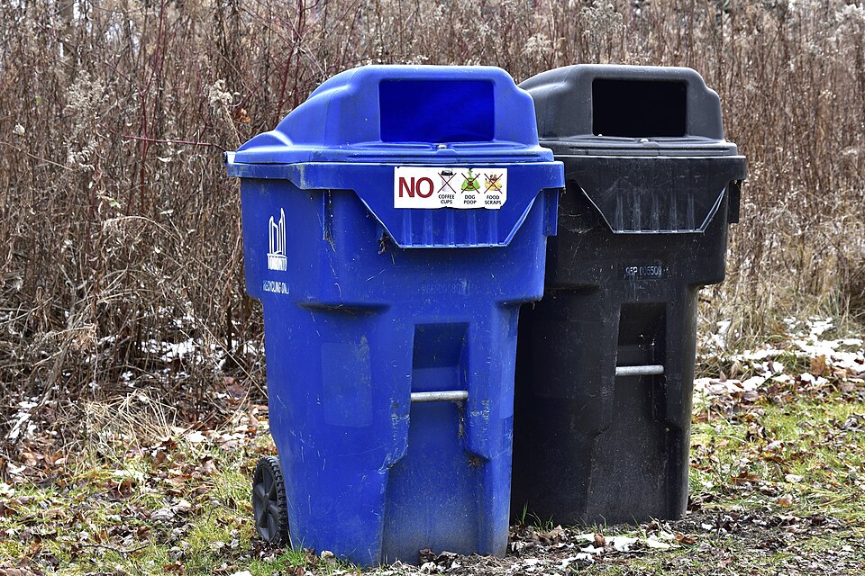 Une poubelle de recyclage (bleue) et une poubelle à ordures (noire) sont mises à la disposition des usagers dans un parc municipal de Toronto, en Ontario.