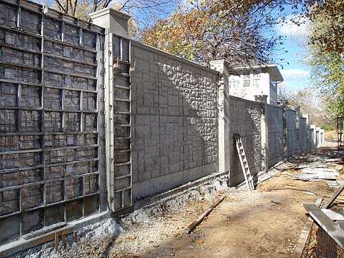 Construction de clôture en béton utilisant des coffrages en aluminium pour donner une impression de pierre de taille au produit fini