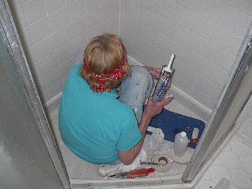 Réparer les carreaux endommagés dans une cabine de douche avec un pistolet à calfeutrer