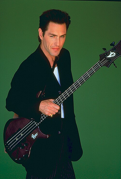 Un homme avec une guitare basse sur un fond vert