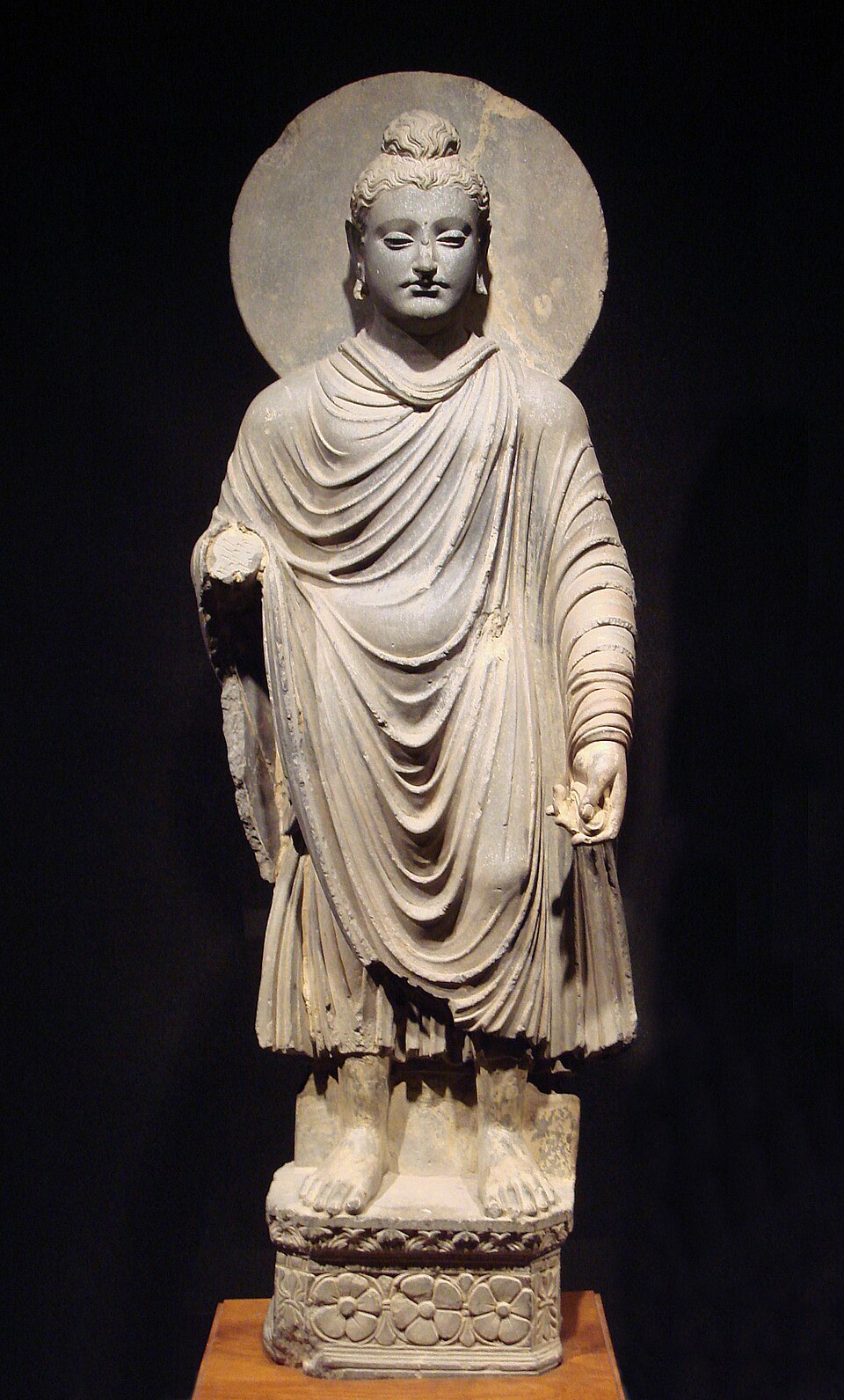 Le Bouddha vêtu d'une robe kāṣāya, originaire de l'Inde ancienne. Ces robes étaient portées par les moines et les nonnes bouddhistes pleinement ordonnés.