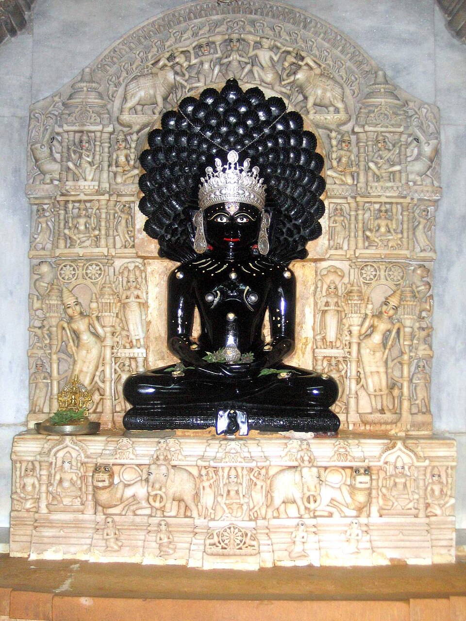 Statue noire de Parshvanatha assis, ornée de fleurs
