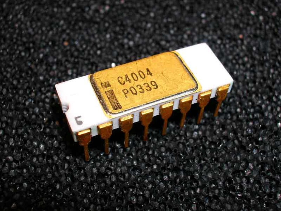 Boîtier DIP en céramique blanche à 16 broches sur mousse noire, portant le logo Intel et la référence C4004.