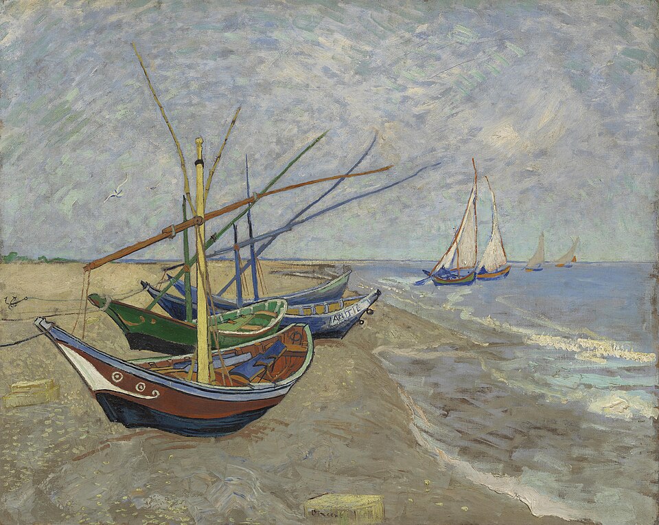 Au loin, quatre bateaux naviguent sur l'eau ; plus près, quatre autres bateaux sont échoués sur le sable sec de la plage.