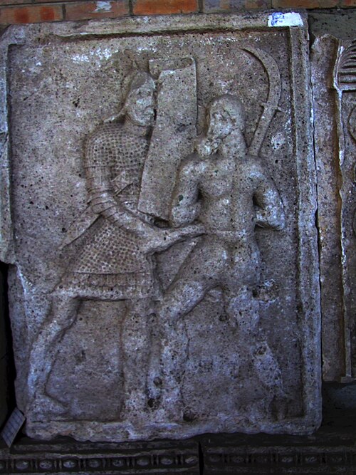 Un faux (romphaia) brandi sur le Tropaeum Traiani
