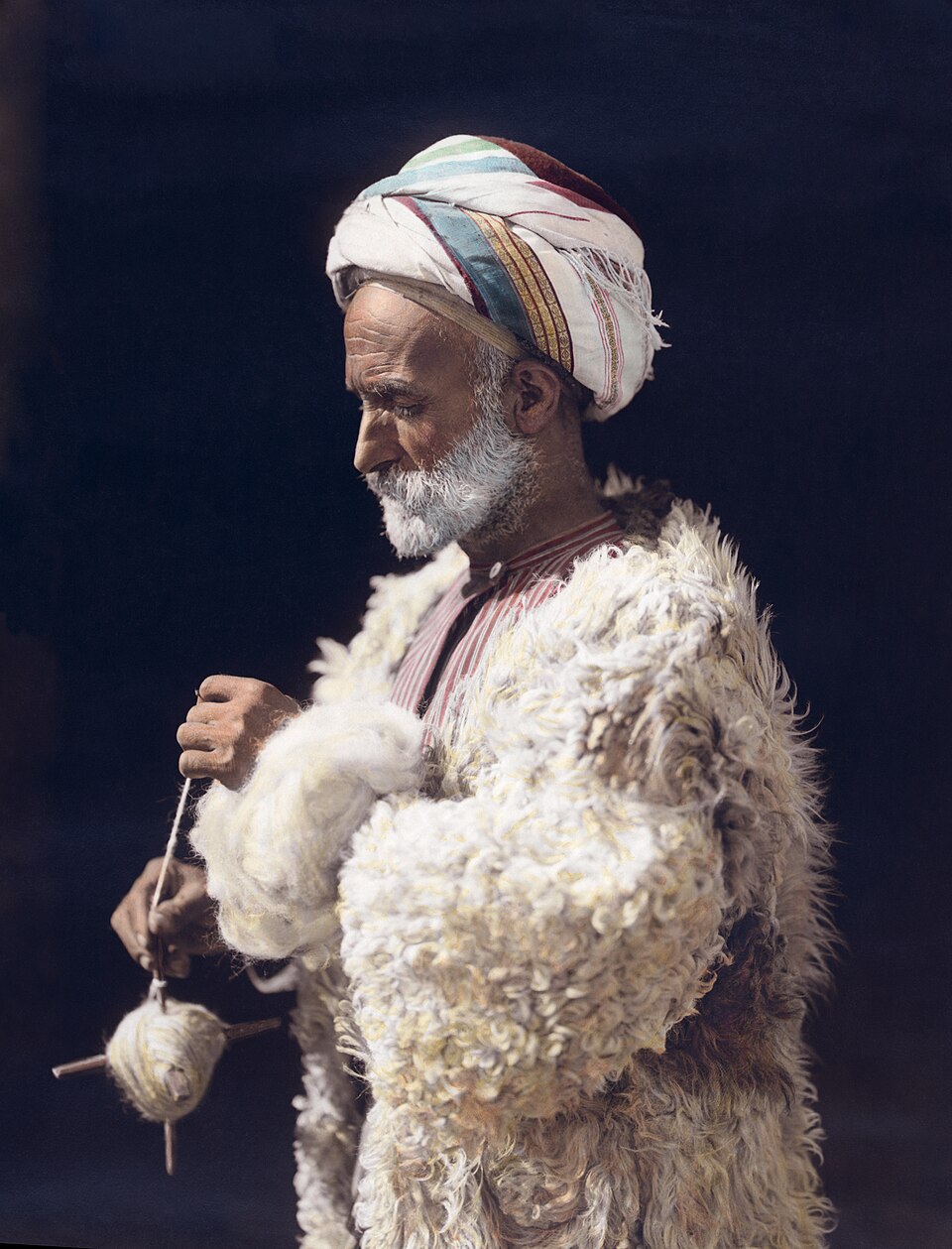 Un homme de Ramallah filant de la laine. Photographie coloriée à la main de 1919, restaurée.